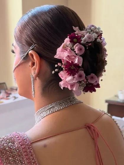 A side view of a floral bun with pink and burgundy flowers, showing the clean lines and how it complements the bride's silver jewelry.