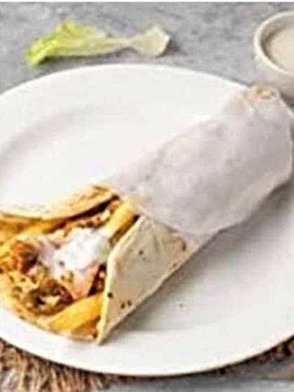 A slightly different angle of the Mexican-style roll, showing the creamy sauce drizzled over the chicken, jalapeños, and fries before it's fully wrapped.