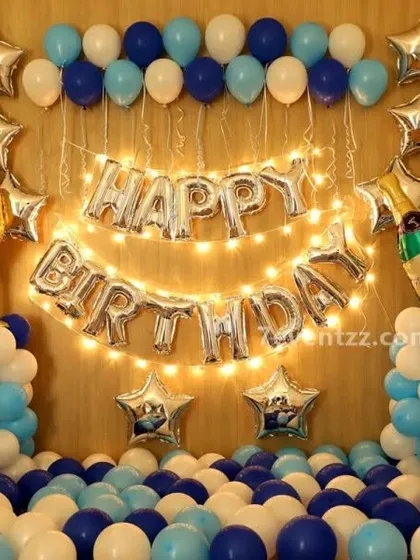 A simple and classic birthday wall decoration. The "HAPPY BIRTHDAY" foil balloons are lit with fairy lights, and framed by blue and white balloon pillars.