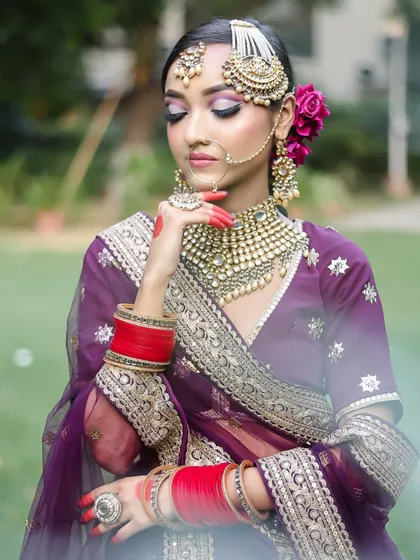 A traditional pose with alta-decorated hands. The makeup is soft and romantic, with a focus on the eyes, perfectly suited for a classic Indian bride.