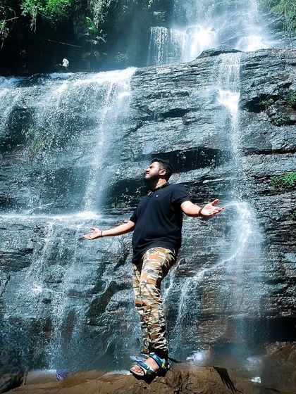 A trekker standing in awe of a powerful waterfall.