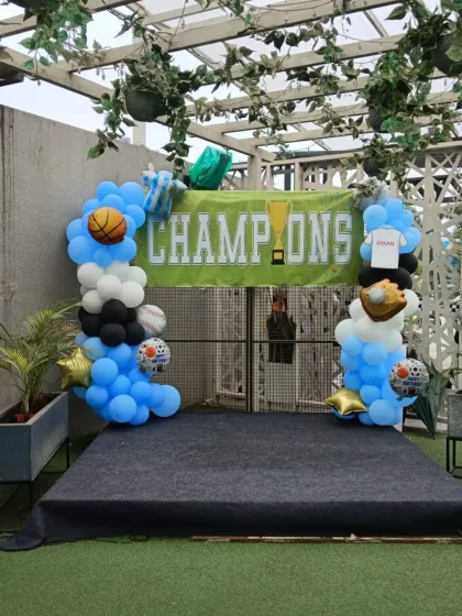 A 'Champions' photo stage for the sports party, complete with a winner's banner and a balloon arch decorated with different sports balls.