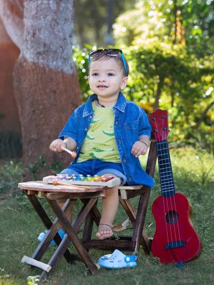 Enjoying the sunshine and some music. This candid shot captures a relaxed moment during an outdoor baby shoot, complete with a toy guitar and xylophone.