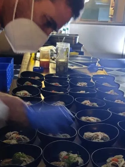 Chef Chris in action, plating bowls during a busy sit-down dinner service. We ensure a seamless experience, bringing the professionalism of a restaurant kitchen to your event.