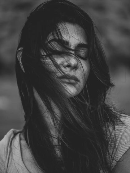 The wind blowing through the model's hair creates a powerful sense of movement and emotion in this black and white portrait. With eyes closed, the image feels introspective and raw, focusing on the feeling rather than a direct gaze.