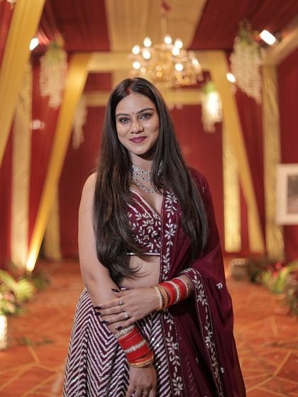 A full-length portrait of the client in the maroon chevron lehenga.