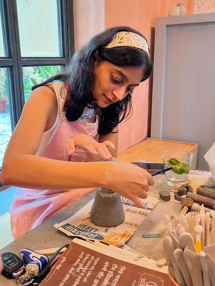 A student carefully works on her hand-built piece, completely absorbed in the creative process.