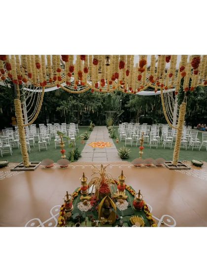 A view from the main altar, looking down the aisle. The floor is decorated with traditional Kolam patterns, and the entire space is framed by the magnificent floral mandap.