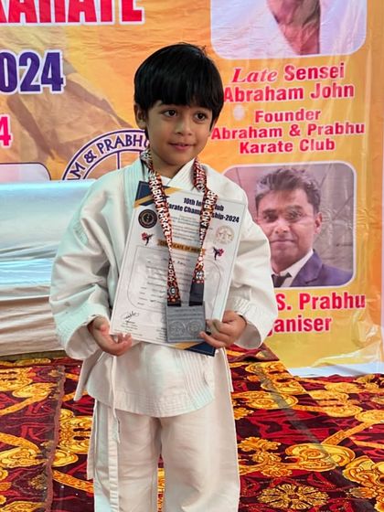 A young student stands proudly with his medals and certificate. These achievements are a testament to his dedication and our academy's training.
