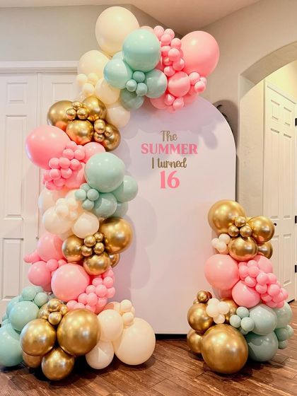 A trendy "The Summer I turned 16" birthday theme. This setup features a modern arched backdrop and an organic balloon garland in a beautiful pastel pink, mint, and gold color scheme.