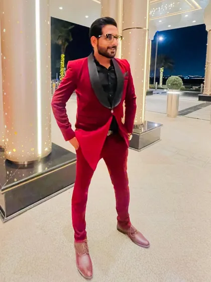 A stylish pose in a velvet red tuxedo before hosting a grand reception in Dubai. My presentation is a key part of the premium hosting service I provide.