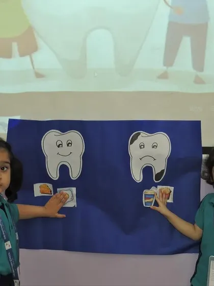 Two students demonstrate the difference between healthy and unhealthy teeth. We use visual aids to teach important lessons about oral hygiene and making good food choices.