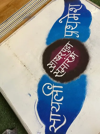 I create personalized floor art for special family occasions. This design was for a 'Sakharpuda' or engagement ceremony, featuring the names of the couple, Sayali and Prathamesh, in elegant Marathi calligraphy.