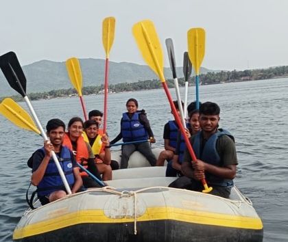 A group in a raft raises their paddles, full of energy during the water sports course in Karwar.