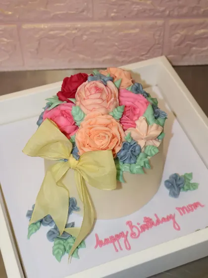 A beautiful bouquet of buttercream flowers in soft pastel shades, finished with a lovely yellow bow. This cake is a garden of love for a special mom's birthday.
