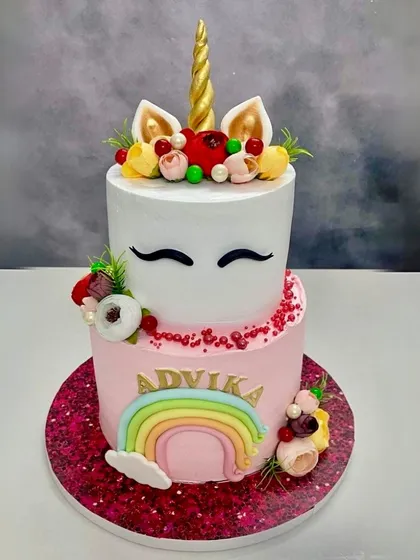 A dreamy two-tier unicorn cake with a rainbow and floral crown. This fondant-covered cake is perfect for a magical princess party.