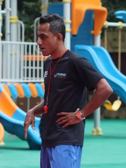 A coach with a whistle, observing players and ready to guide them. Our coaching is about turning dreams into reality through hard work.