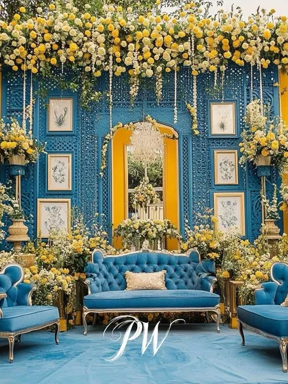 A stunning Mehendi setup in shades of yellow and blue. The vintage-style furniture and intricate floral backdrop create a look of royal elegance.