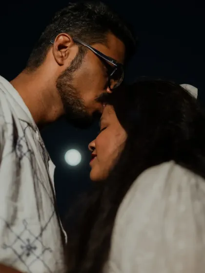 A romantic close-up of a forehead kiss, with the moon visible in the background, creating a magical and dreamy pre-wedding photo.