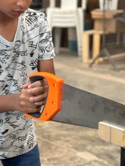 A young maker learning to use a hand saw correctly and safely. Building foundational skills early gives kids the confidence to tackle more complex projects later on.