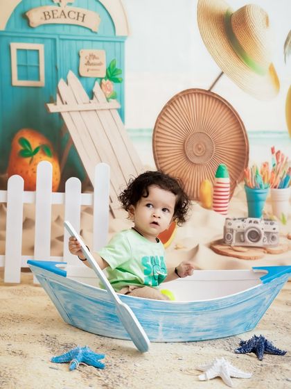 Ready to row! This little one is exploring the boat prop in our beach setup, creating a cute and curious portrait.
