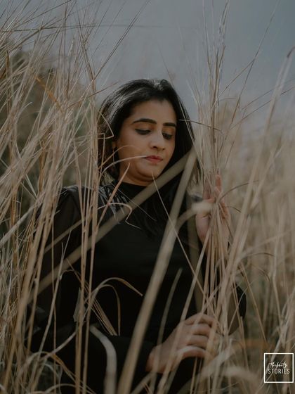 A pensive and beautiful portrait of the bride amidst tall, dry grass. The earthy tones and her quiet expression create a very artistic and soulful image.
