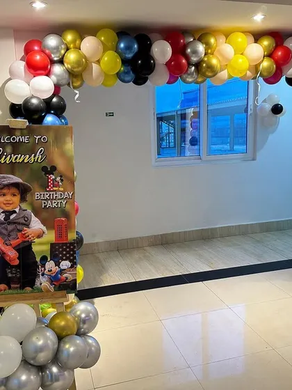 A welcome entrance for a Mickey Mouse party. The balloon arch and personalized sign with the birthday boy's photo create a warm and inviting atmosphere.