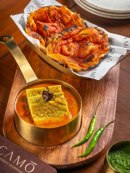 A unique layered dish in a savory gravy, served with a crispy, red-hued paratha for Camo Noida.