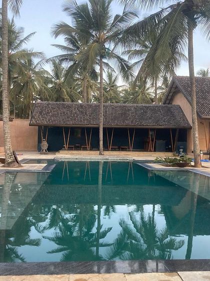 The main house and pool at the Hassan farmhouse, a tranquil oasis surrounded by coconut palms.
