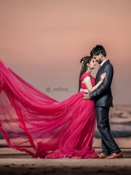 A perfect pre-wedding moment captured at sunset. This pink trail gown stands out against the ocean backdrop, and its fabric is ideal for creating that windswept, romantic look that couples love for their beach photoshoots.