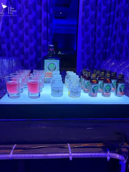 A glowing shot bar ready for the party. This setup features rows of colorful shots and mini bottles of Don Julio and Jagermeister, all illuminated for a cool, modern look.