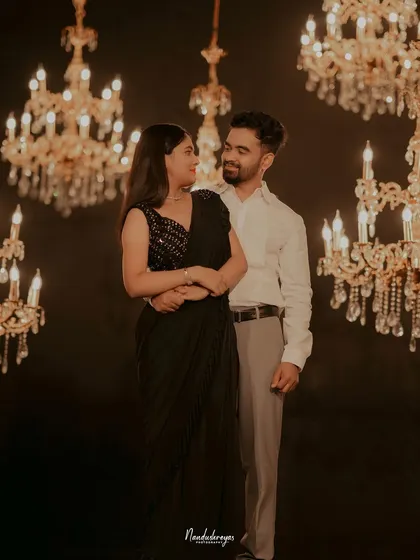 A romantic portrait of a couple surrounded by glowing chandeliers, creating a warm and opulent atmosphere.