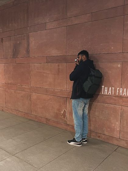 Me leaning against the wall, taking a moment to find the perfect angle for the shot. It illustrates the patience required in photography.