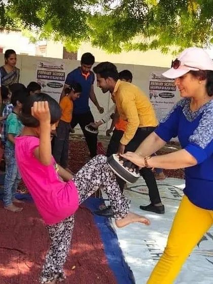 A young girl practices her kicks on a pad during our community outreach program. We teach practical skills in a supportive environment.