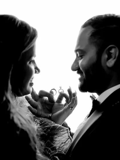 A creative black and white shot where the couple holds up their engagement rings, perfectly framed between them.