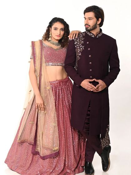 This pose showcases the beautiful embroidery on the shoulder of the men's sherwani and the shimmer of the sequined lehenga, ideal for a professional shoot.