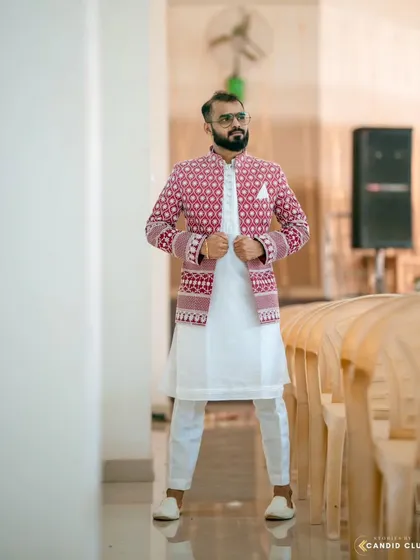 I love seeing my clients own their look. This custom-made open Jodhpuri jacket features bold red and white embroidery, layered over a simple white kurta set for a sharp, celebratory feel.