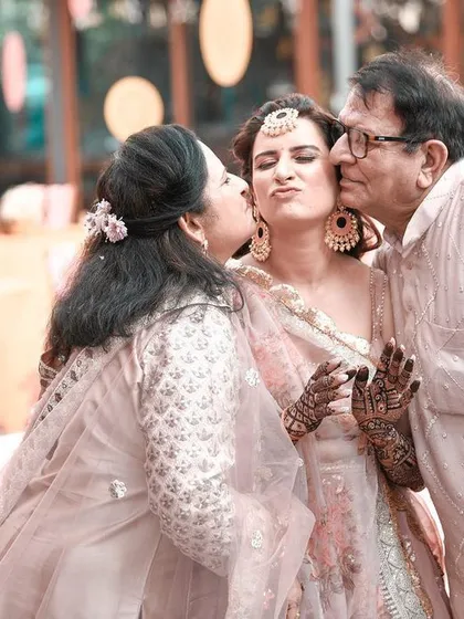 Some of the most powerful wedding photos are the ones with family. This candid shot of a bride receiving kisses from her parents is full of genuine emotion and tells a story of love, blessings, and a new beginning.