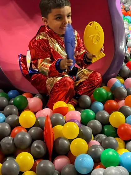 A young superhero enjoying the ball pit after coming down the monster slide.