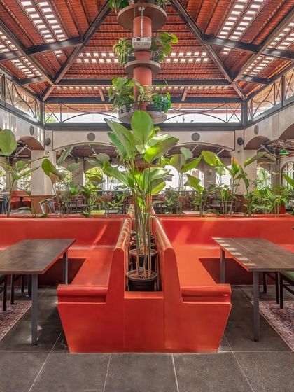 The central seating at Adda 1522 is defined by bold, red-oxide finished "katte" seats that incorporate planters. Above, the roof made of traditional Mangalore tiles and glass inserts allows natural light to filter through, creating a bright, semi-open-air feel.