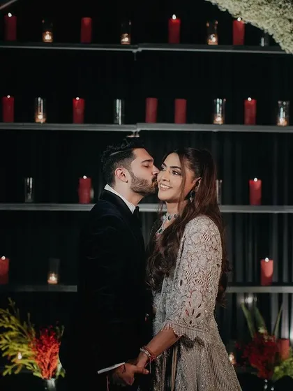 A romantic moment from a cocktail night. The groom's affectionate kiss and the backdrop of red candles create a warm, intimate atmosphere that is both sweet and stylish.