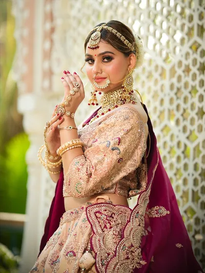A confident pose that highlights the intricate details of the bride's outfit and jewelry. The makeup is designed to be sweat-proof and long-lasting.