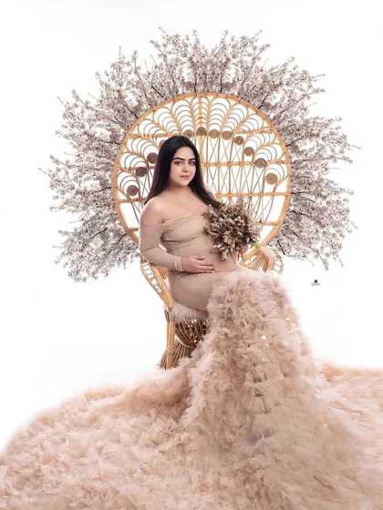 A full view of the peacock chair setup, showcasing the incredible volume of the beige ruffled gown. This is a perfect example of the glamorous and customized sets I can create.