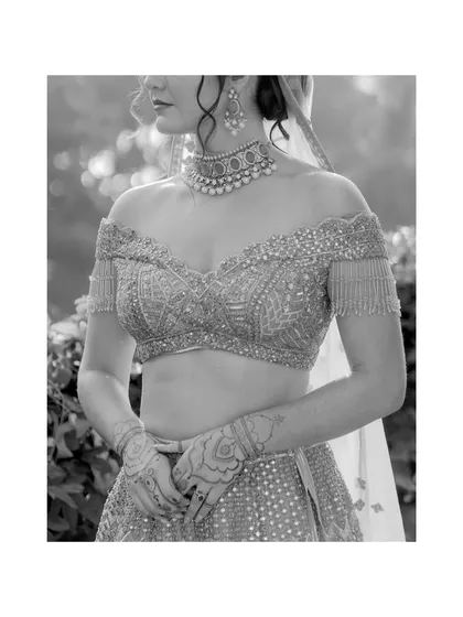 A detailed black and white shot of the bride's off-the-shoulder blouse and intricate henna. This portrait focuses on the beautiful craftsmanship of her wedding look.