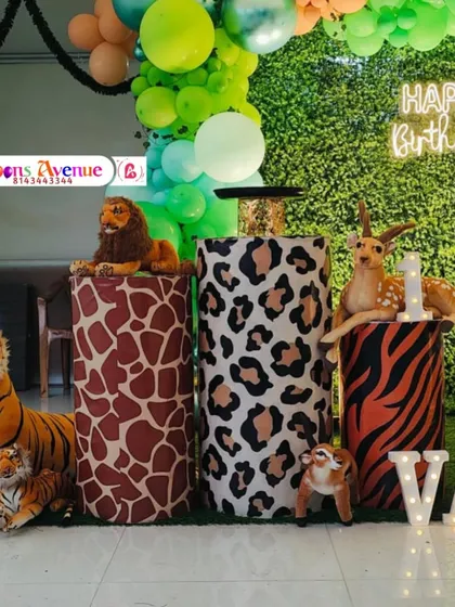 A closer view of the animal-themed cake stands and props. The pedestals are wrapped in giraffe, leopard, and tiger prints, perfectly matching the safari party concept.