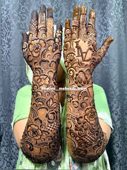 This design features the initial 'A' on one palm, surrounded by dense and beautiful patterns.