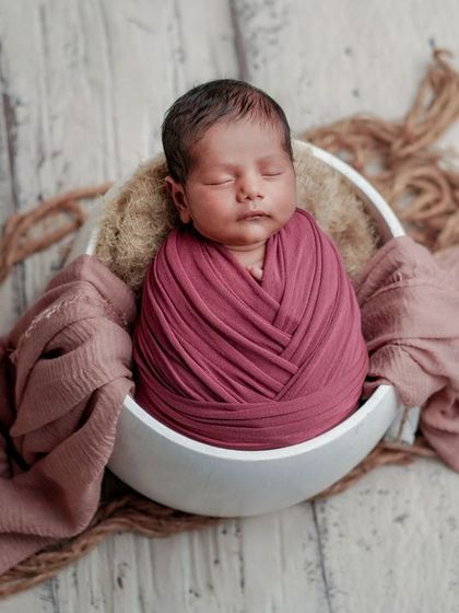 A simple and pure portrait. This baby is swaddled in a neutral color, allowing their sweet, sleeping face to be the only focus.