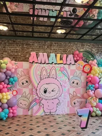 A fun and quirky bunny theme for a 7th birthday. This setup features a sequin backdrop, colorful balloons, and a cool, modern cartoon aesthetic.