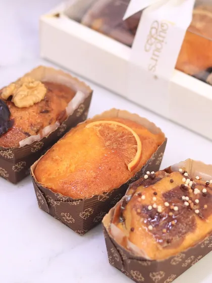 A set of three mini travel tea cakes, featuring date and walnut, orange, and marble chocolate flavors. These are perfect for gifting individually or as part of a larger hamper, offering a taste of classic baking.
