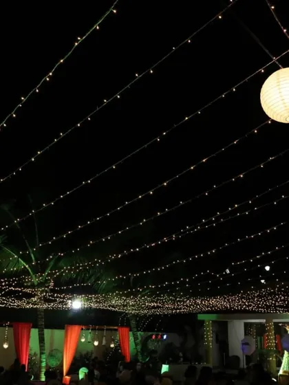 Even simple lighting can be impactful. Here, a dense canopy of fairy lights creates a starry night effect over an outdoor seating area, with paper lanterns adding a soft, ambient glow for a relaxed corporate mixer.